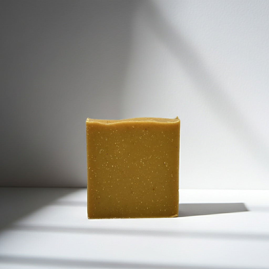 Square bar of Turmeric soap on a white surface with a gray background