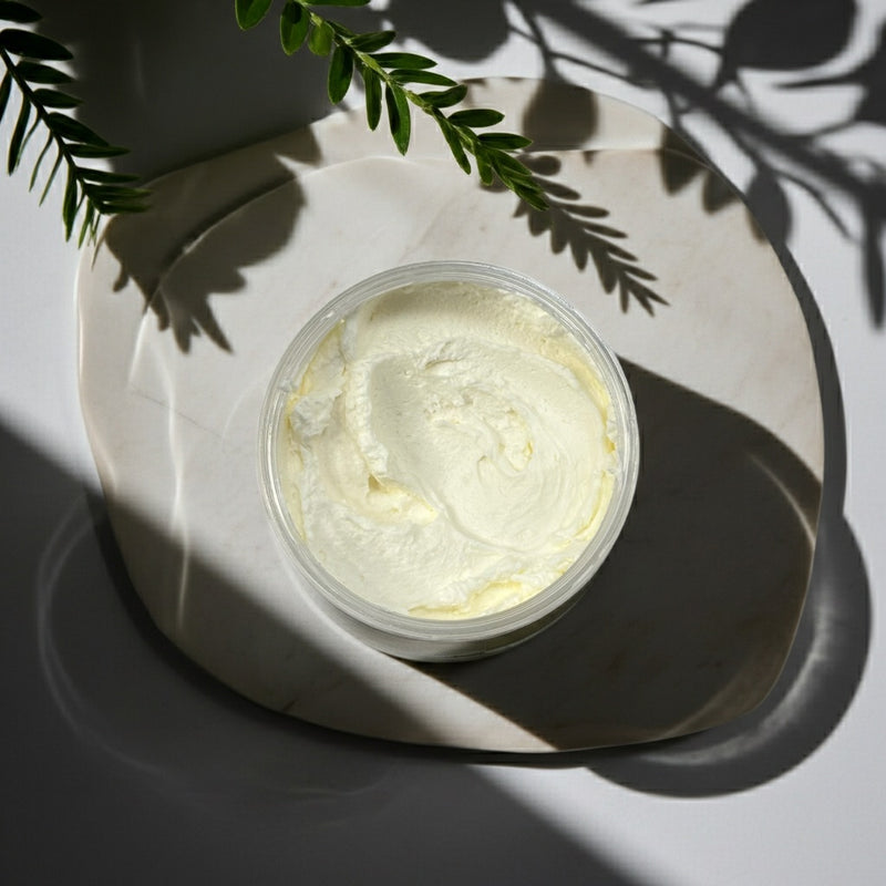 Jar of Lavender Flower body butter on a marble surface with green leaves